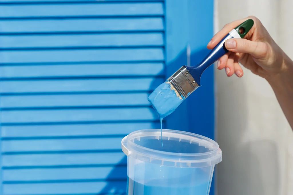 hand holding paintbrush with dripping blue paint o 2026 09 25 05 44 38 utc
