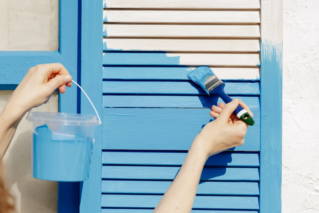 hands painting wooden window shutters blue in brig 2026 09 25 05 44 38 utc