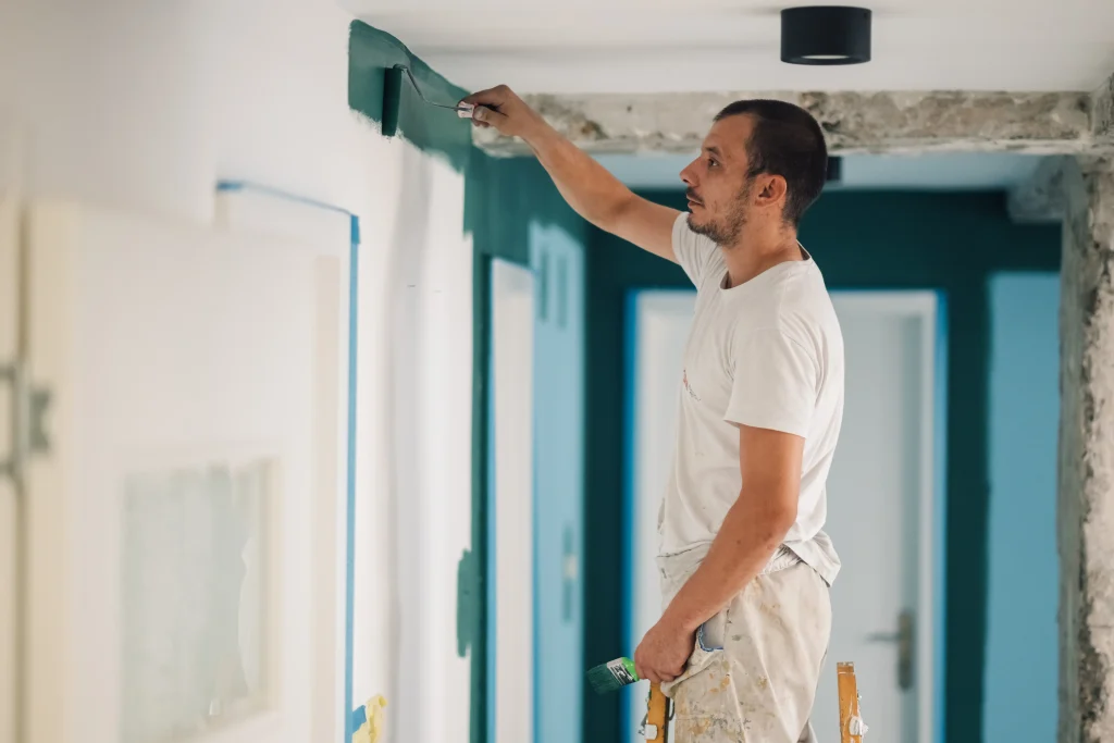 man painting wall in green color inside home 2026 09 22 05 27 46 utc