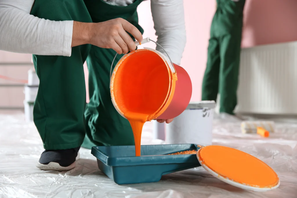 painter pouring orange paint into a paint tray 2026 09 22 16 02 28 utc