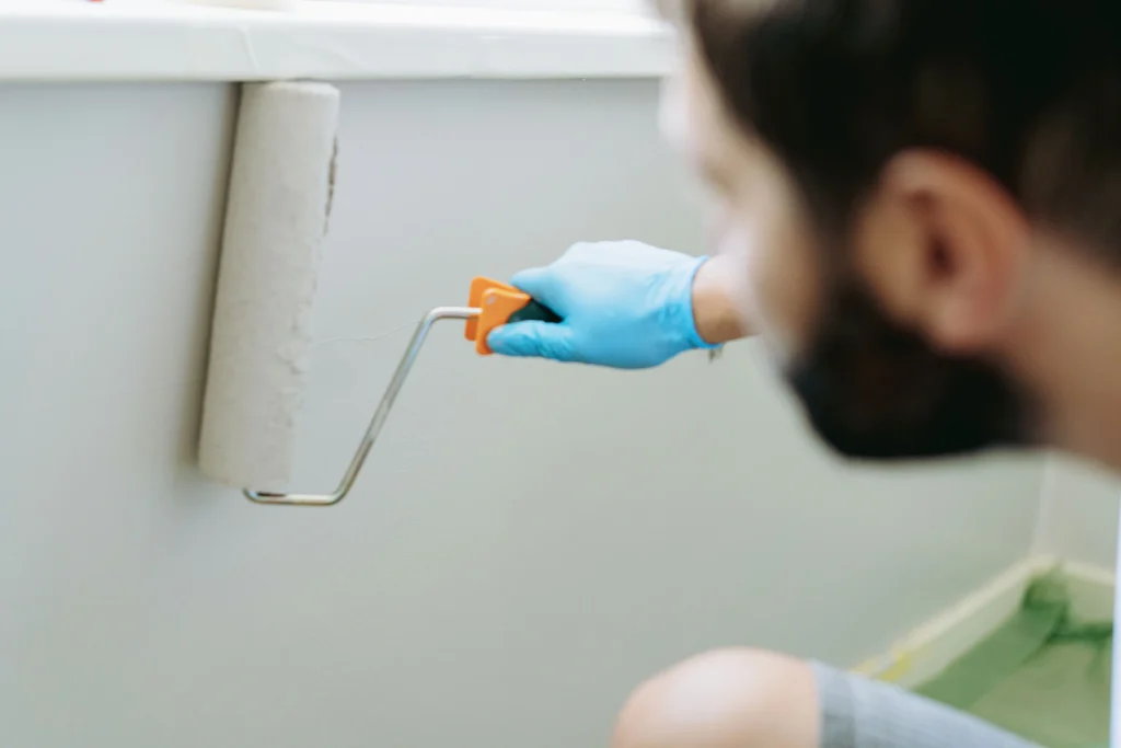person paints a wall using roller brush indoors 2026 09 21 23 03 16 utc